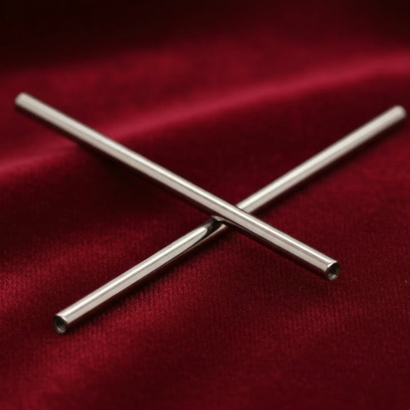 Two metallic straws crossed on a beige woven surface