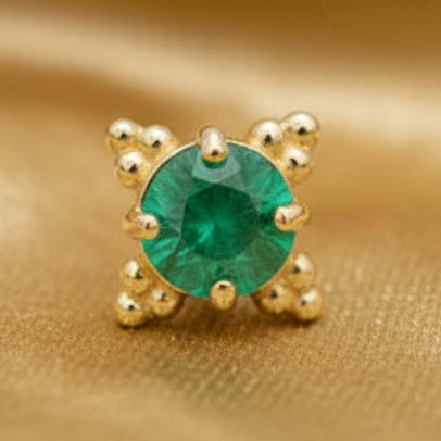 Gold earring with a green gemstone on a white background