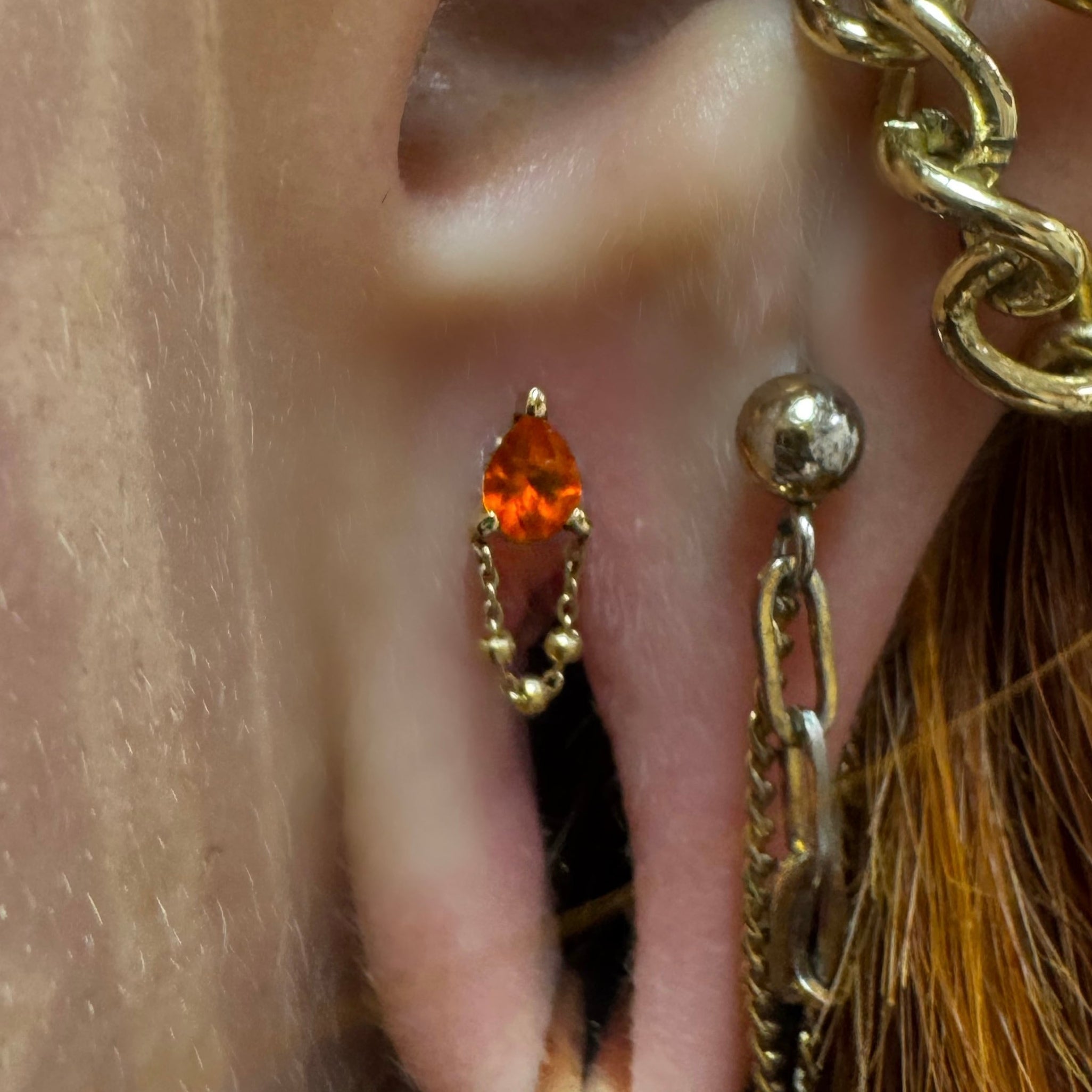 Close-up of an ear with multiple gold earrings and a visible tattoo.