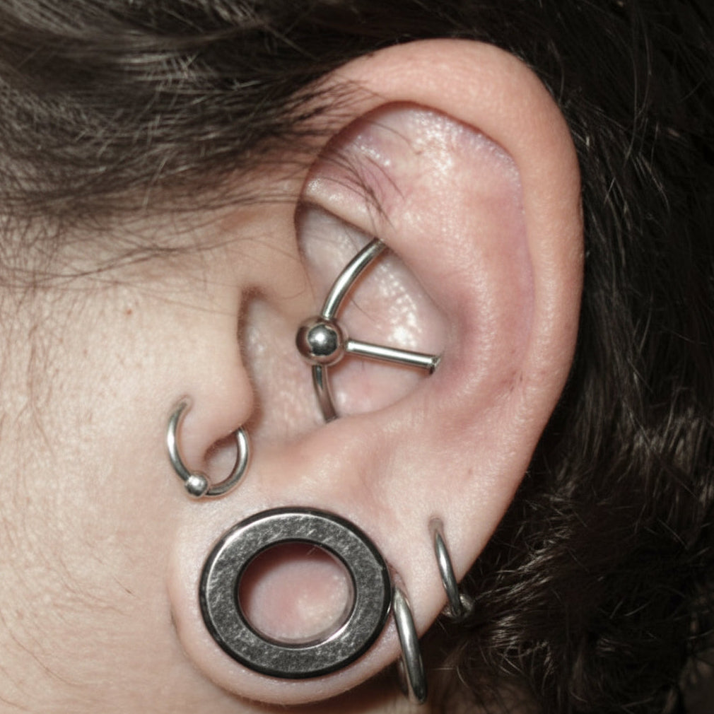 Close-up of an ear with multiple silver earrings
