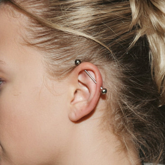 Close-up of a person with styled hair and earrings against a dark background