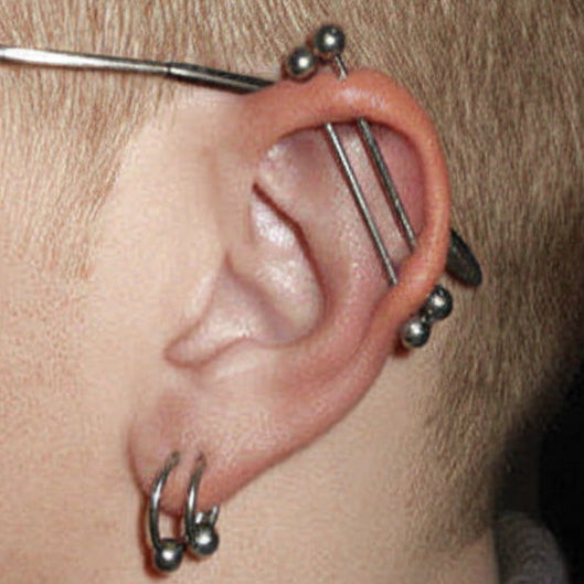 Close-up of an ear with multiple earrings on a dark background