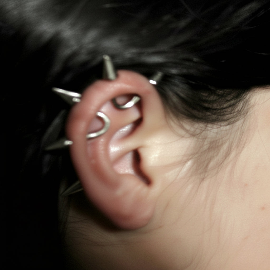 Close-up of an ear with multiple earrings against a dark background