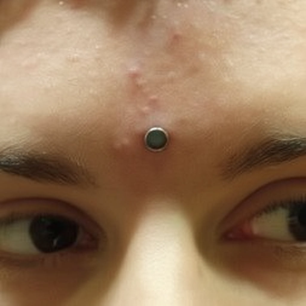 Person with pink hair and piercings wearing a dark beanie and shirt.