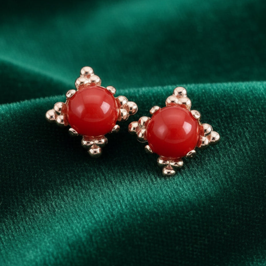 Pair of red earrings with rose gold accents on a white background