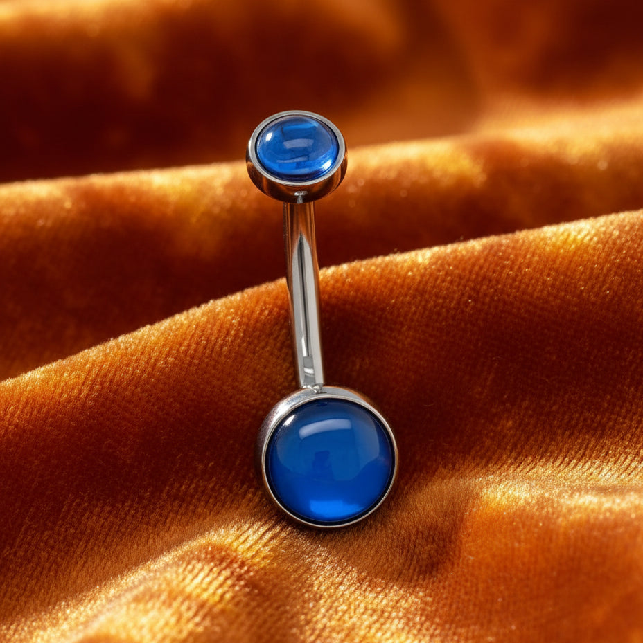 Belly button ring with blue gemstones on a white background
