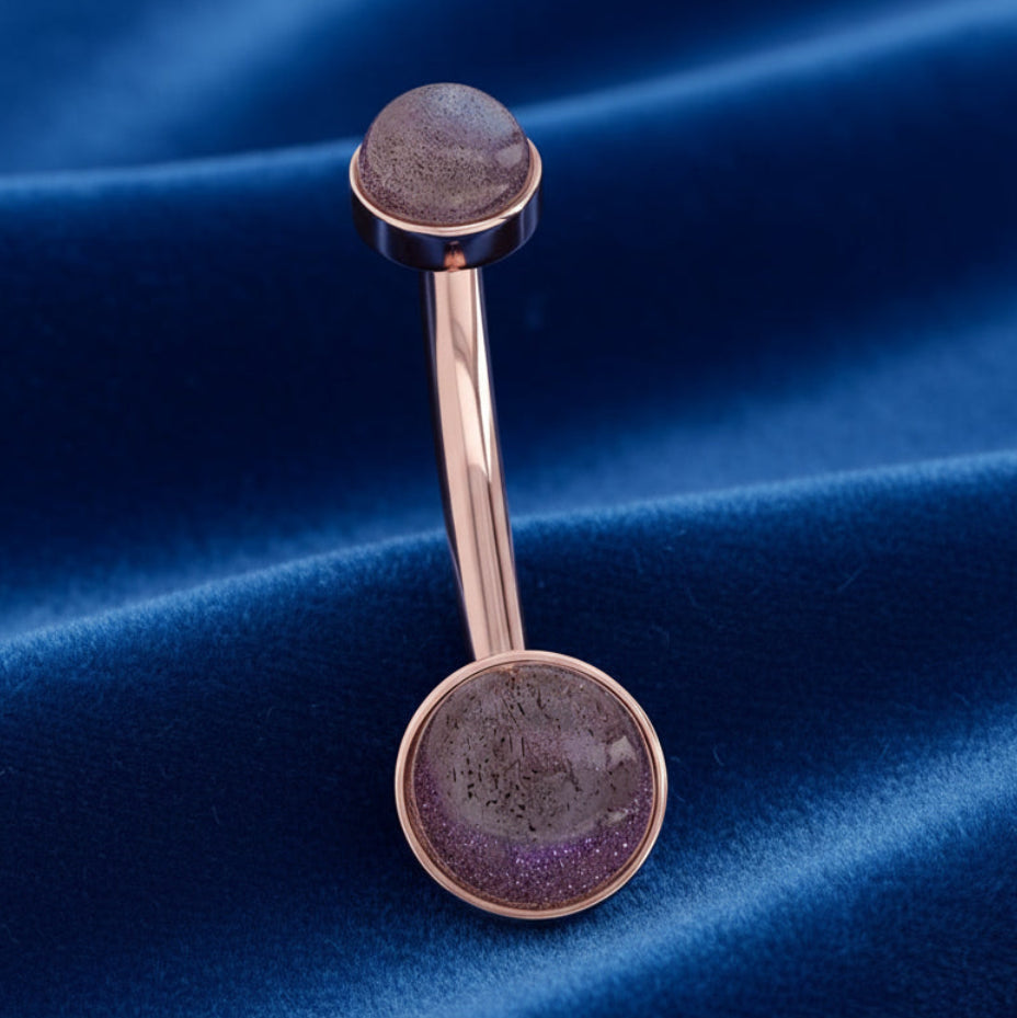 Rose gold belly button ring with a dark stone design on a white background
