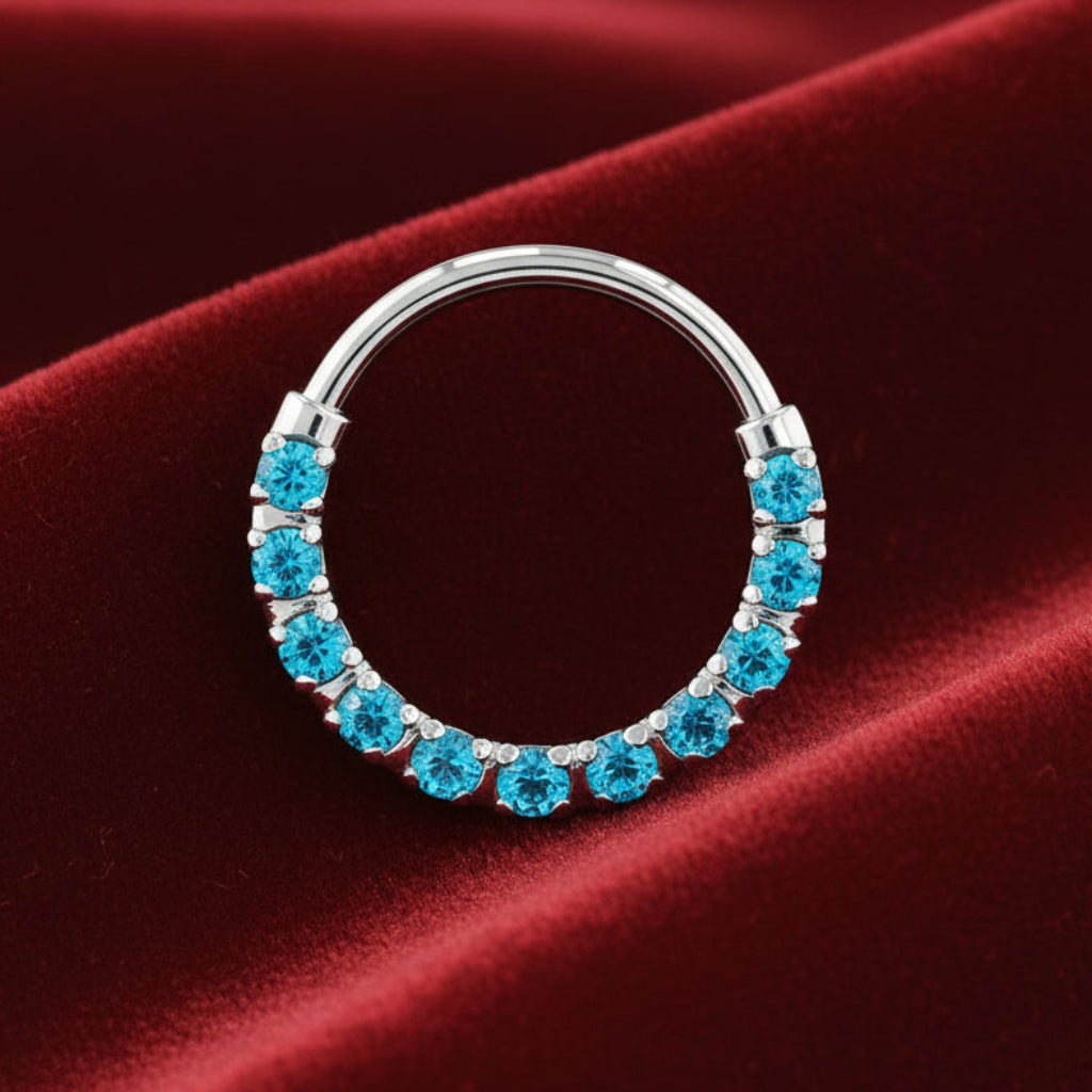 Silver nose ring with blue gemstones on a red satin background