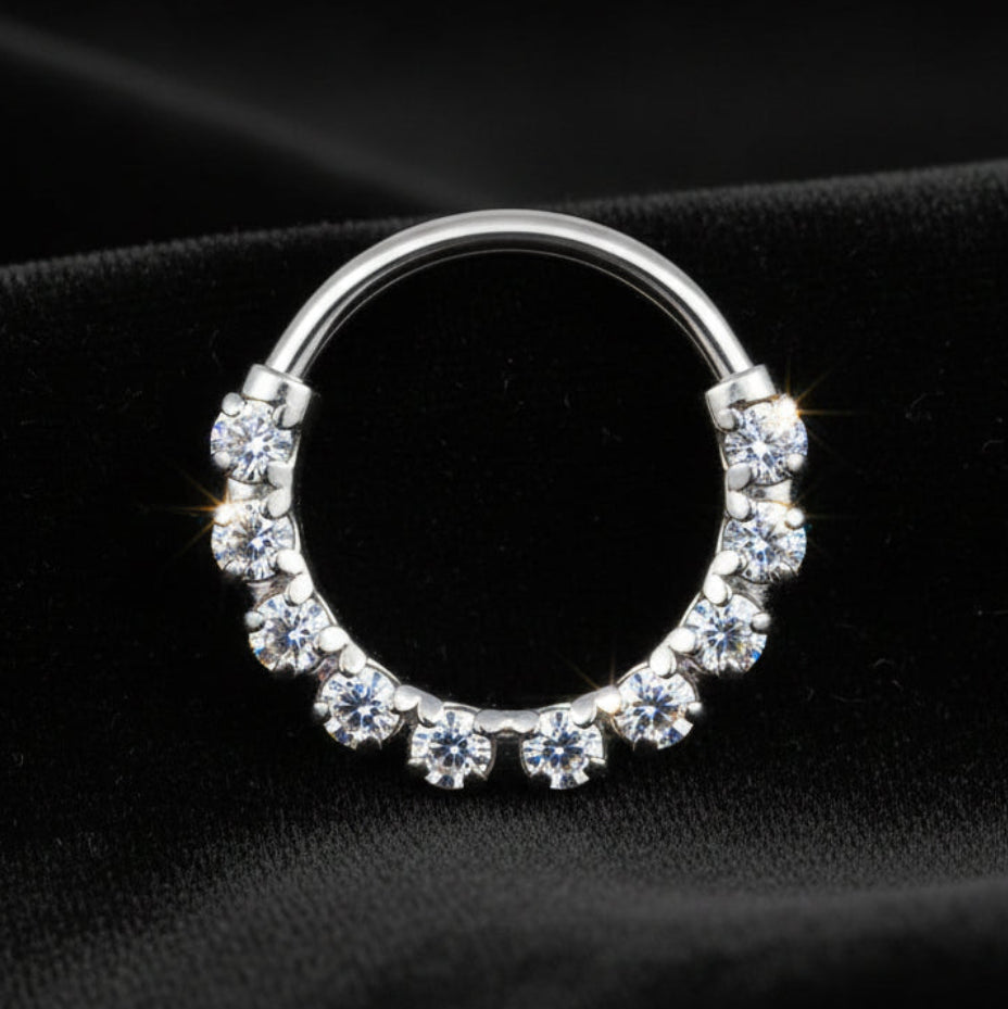 Silver hoop earring with embedded stones on a black fabric background