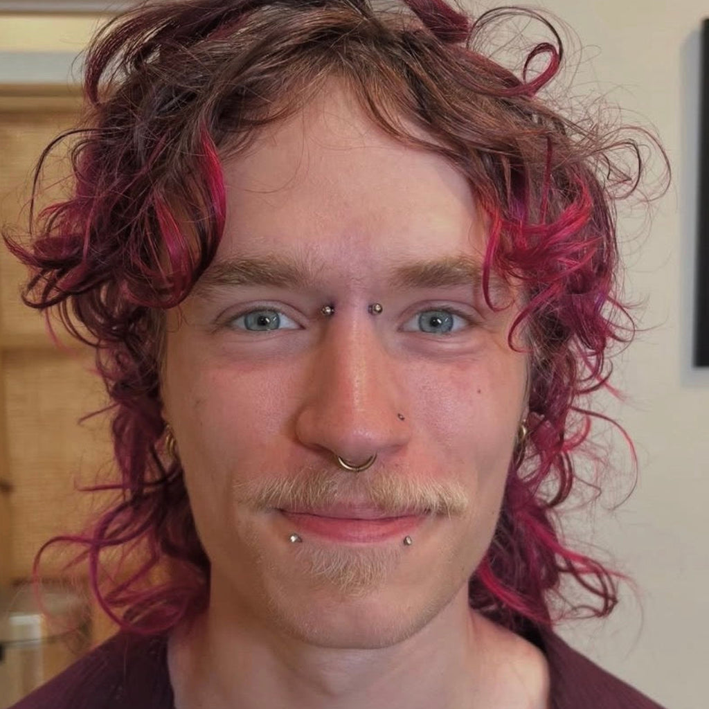Person with red hair and piercings in a casual indoor setting