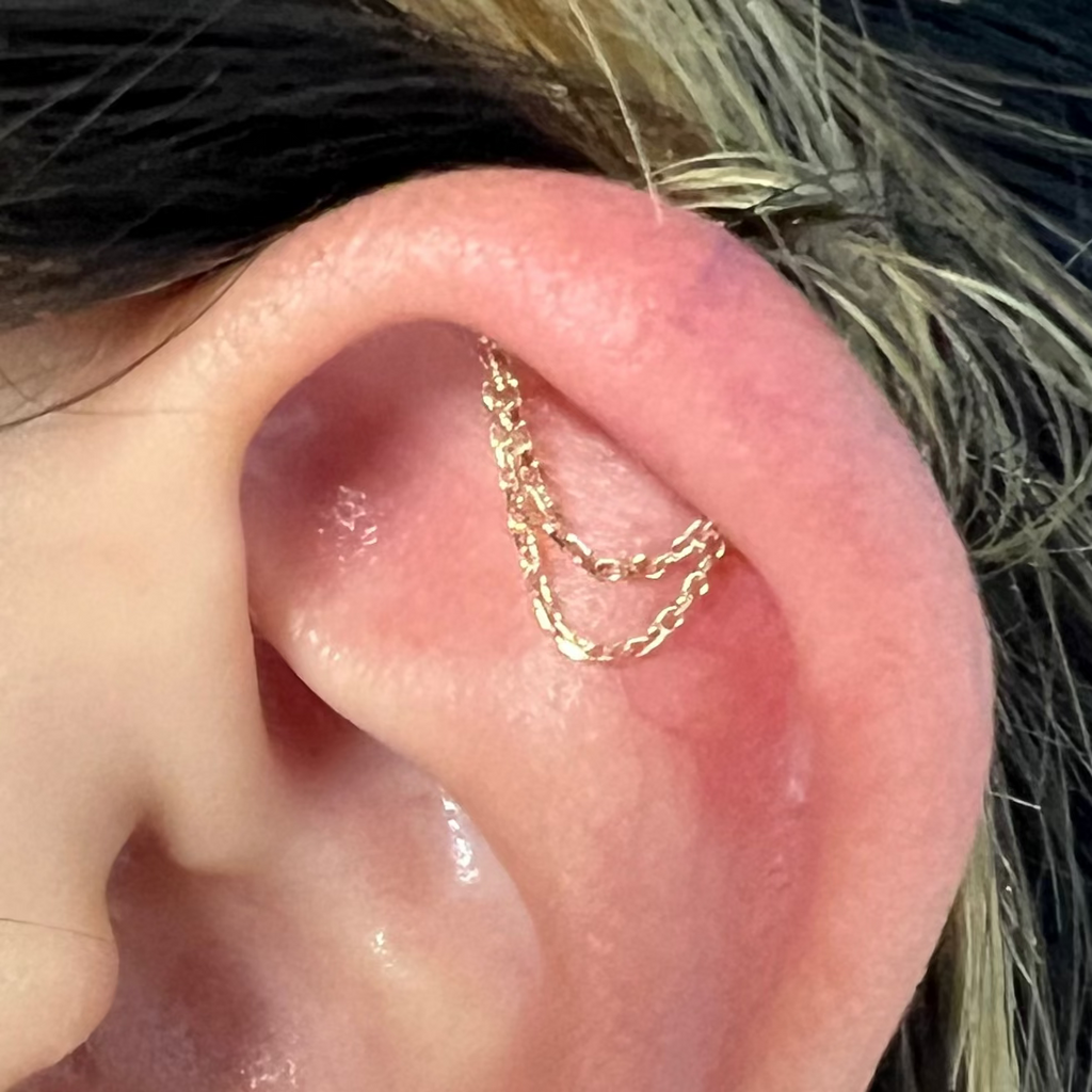 Close-up of an ear with gold hoop earrings and a small stud earring.