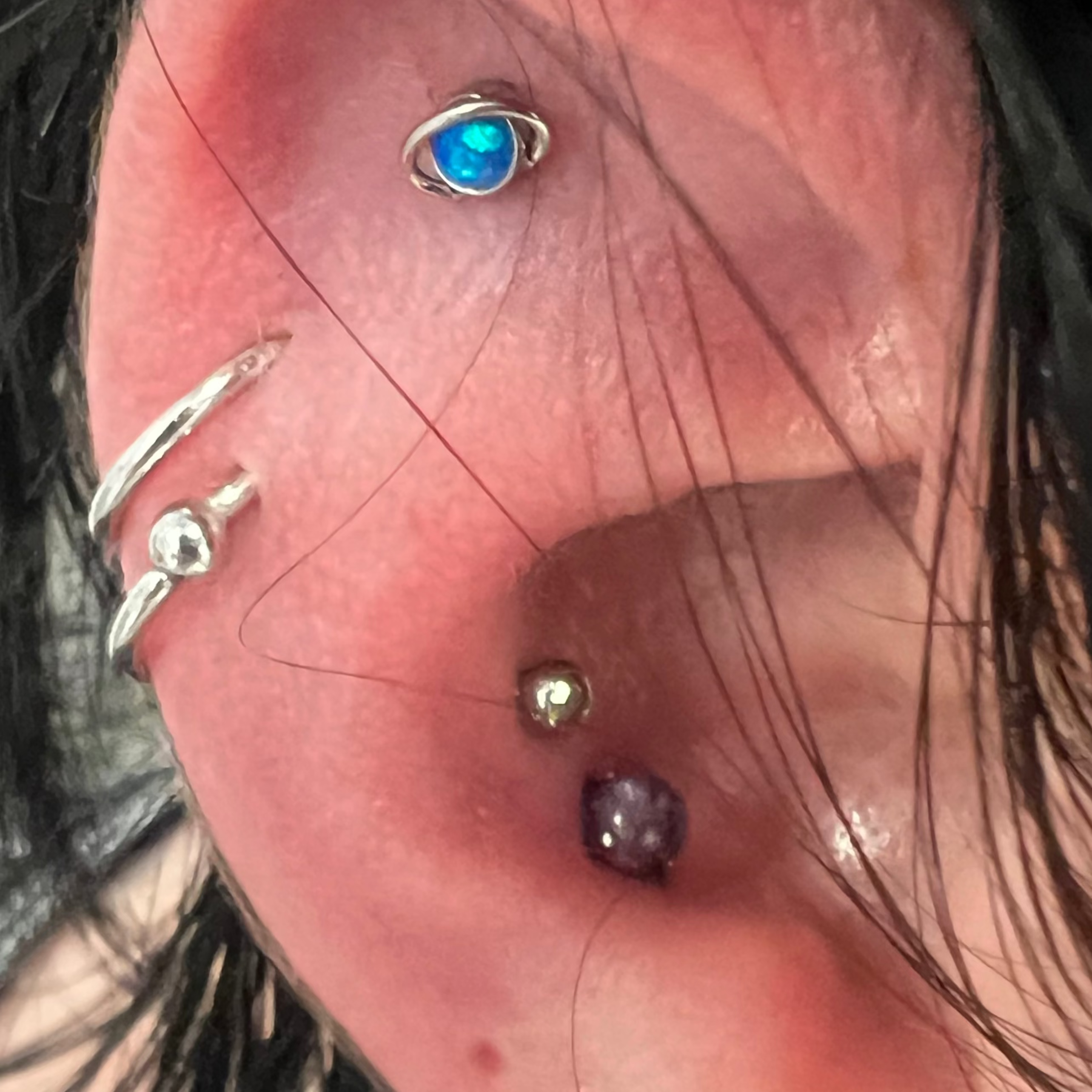 Close-up of an ear with multiple earrings and piercings.