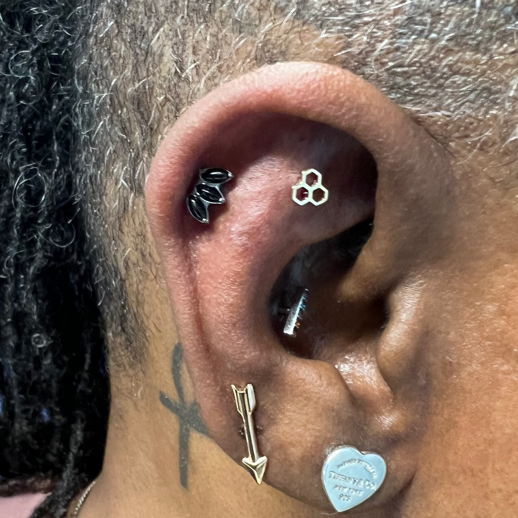 Close-up of an ear with multiple earrings on a person with dark skin.