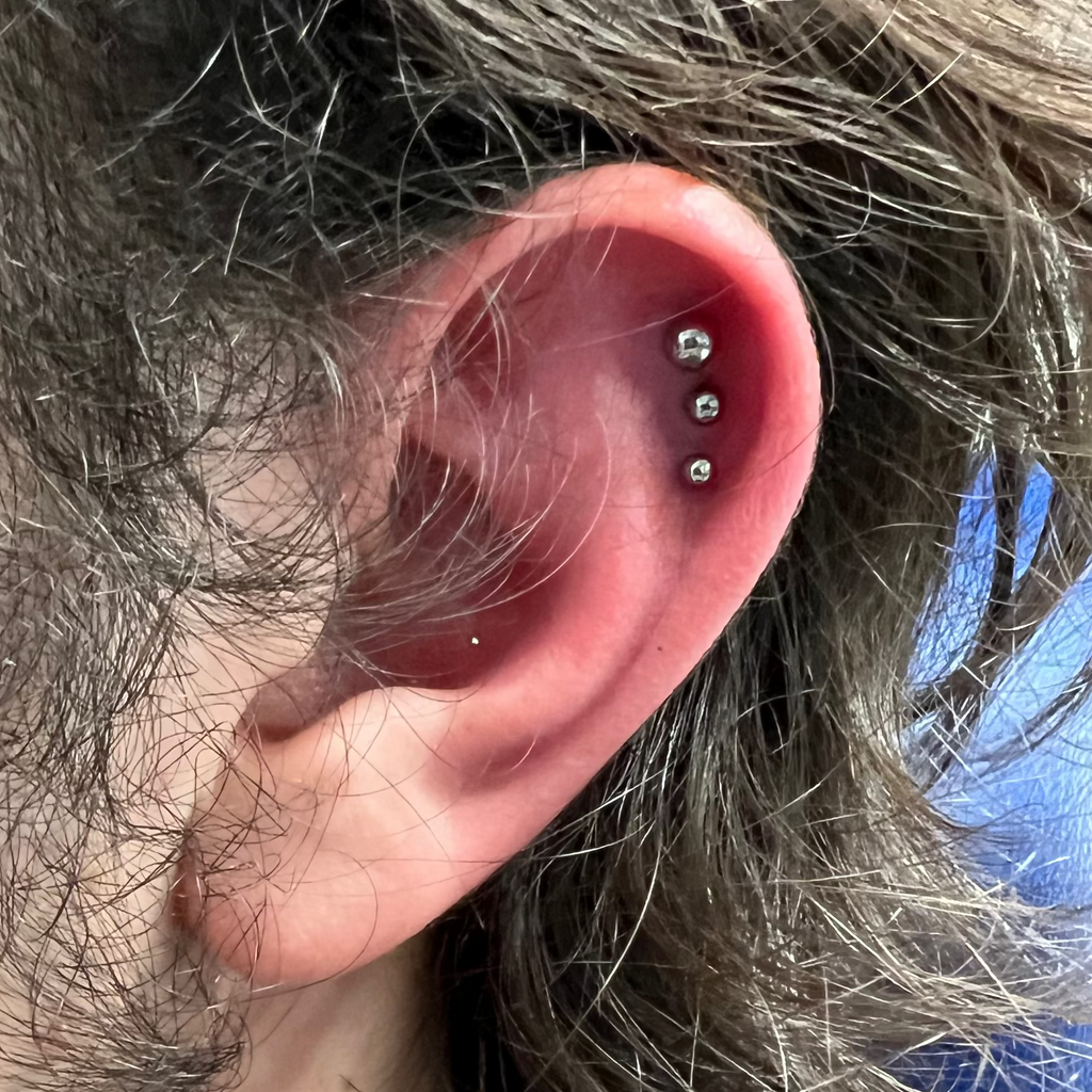 Close-up of an ear with multiple piercings against a blurred background