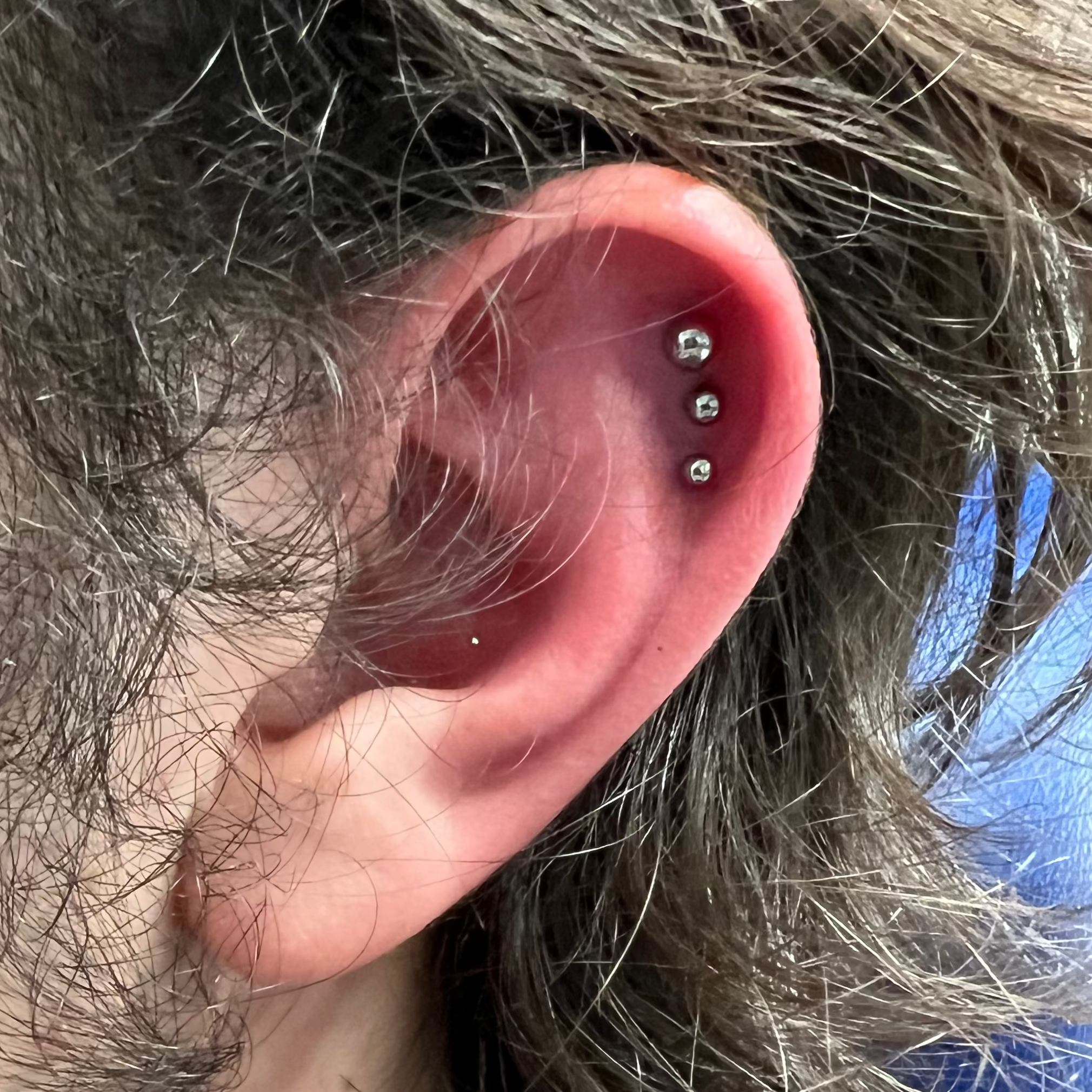 Close-up of an ear with multiple piercings against a blurred background