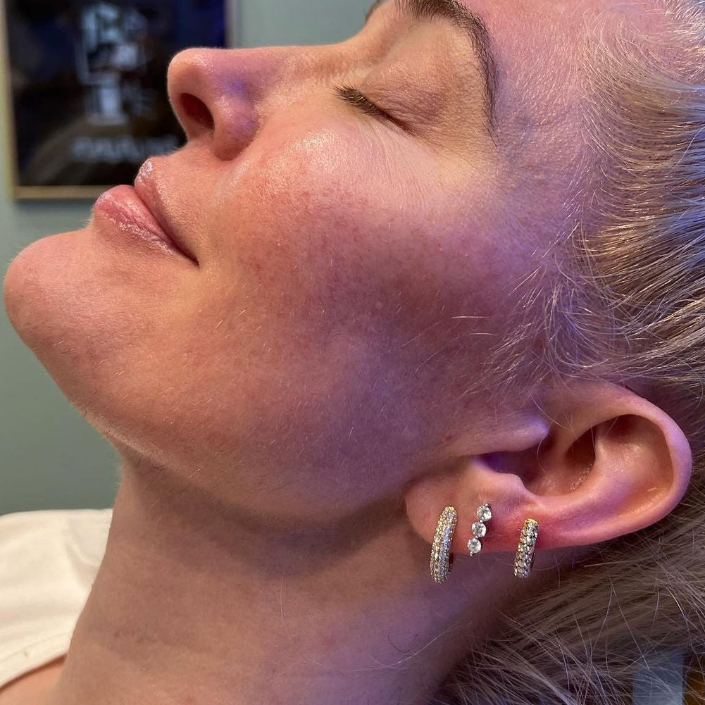 Close-up of a person with styled hair and earrings in a salon setting.