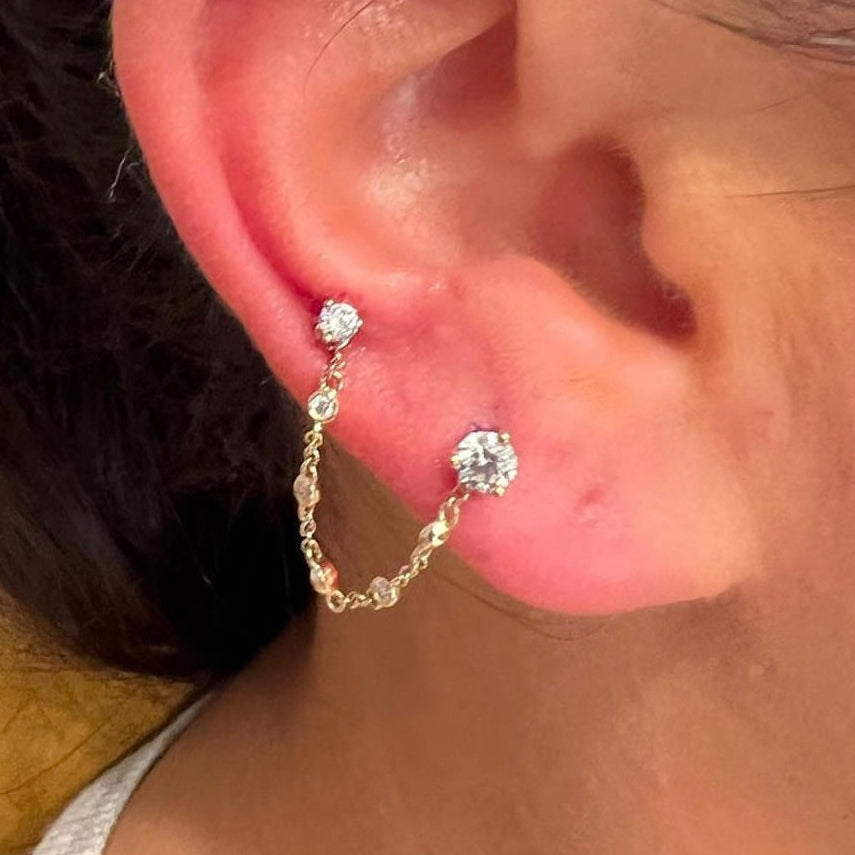 Close-up of an ear wearing a gold hoop earring with a diamond.