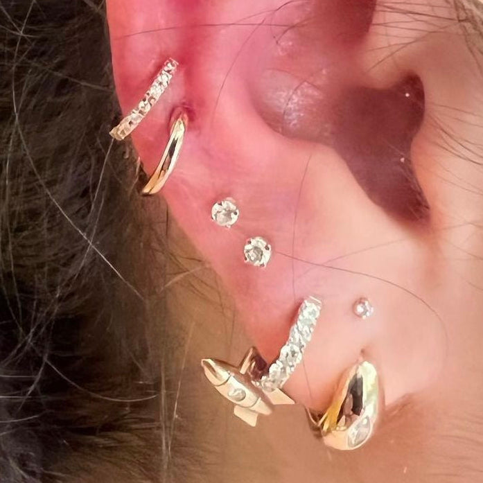 Close-up of an ear with multiple gold and diamond earrings.