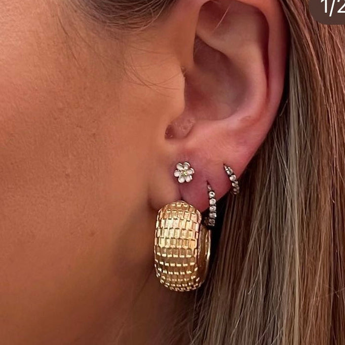 Close-up of a woman wearing gold hoop earrings and necklaces.