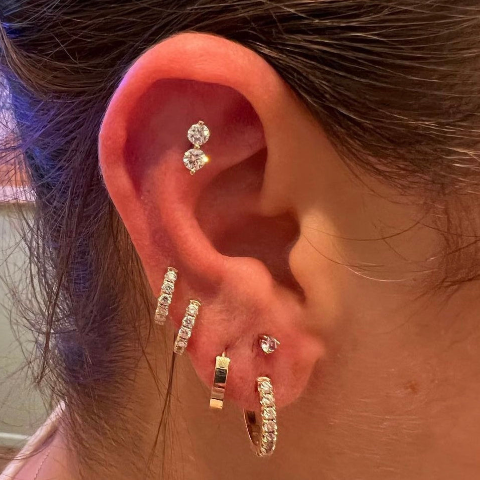 Close-up of an ear with multiple earrings and a gold hoop earring.