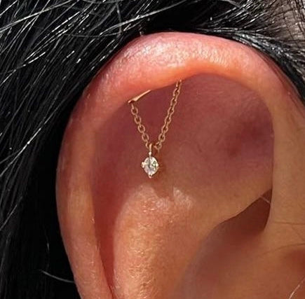 Close-up of an ear wearing multiple diamond earrings with a blurred background