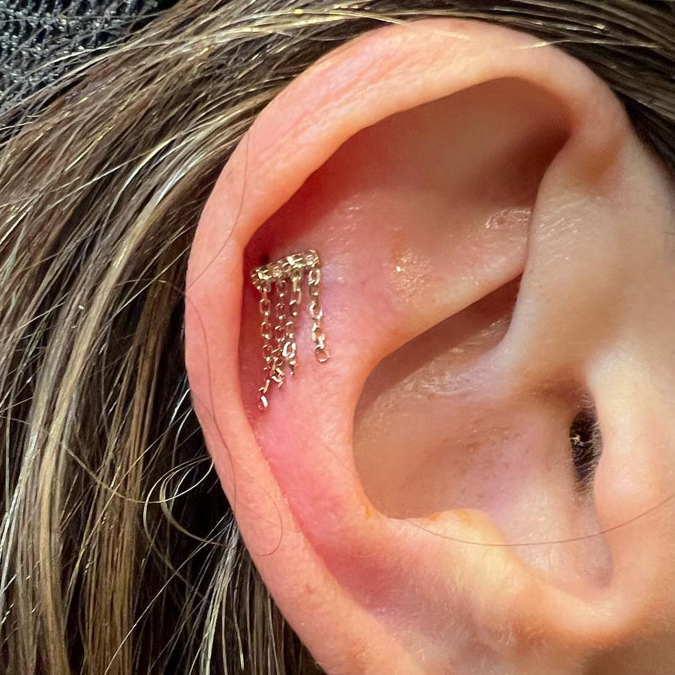 Close-up of an ear with gold earrings and a diamond earring.