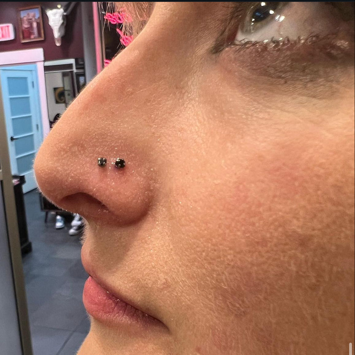 Close-up of a person's face with a nose ring in an indoor setting.