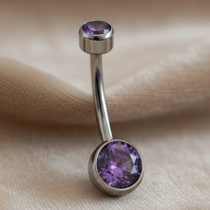 Belly button ring with purple gemstone on a neutral background
