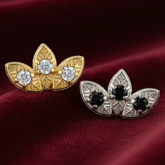 Two pairs of leaf-shaped earrings, one gold and one silver with gemstones, on a white background.