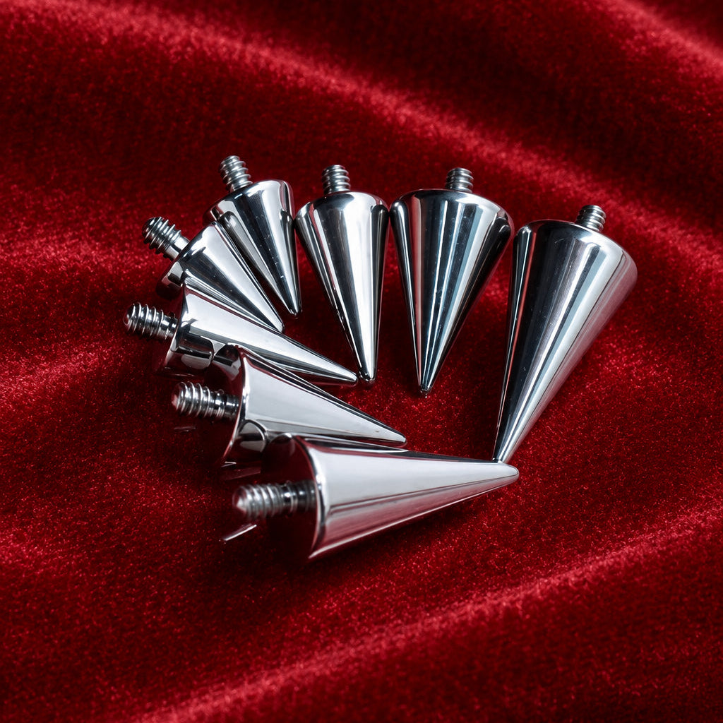 Six metallic silver cone-shaped spikes with threaded screw bases, arranged in a fan shape on a textured red surface.