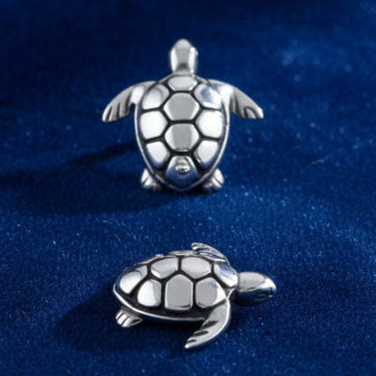 Two silver turtle charms on a white background with 'sterling silver' text.