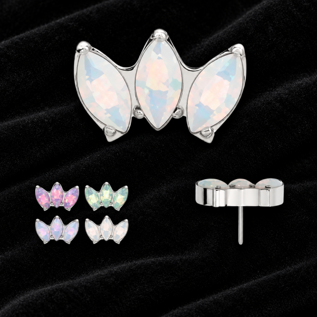 A three-stone butterfly-shaped stud earring with iridescent pale blue opal-like marquise stones in a silver setting, shown on a white background with smaller alternate color options and a post/back view below.