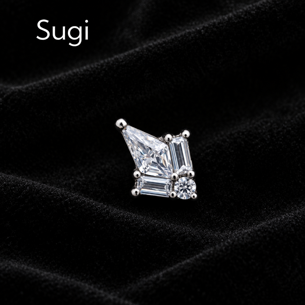 A single silver-toned stud earring featuring a large emerald-cut clear gemstone with smaller accent stones, shown on a plain white background with the brand name 'Sugi' in the top left corner.