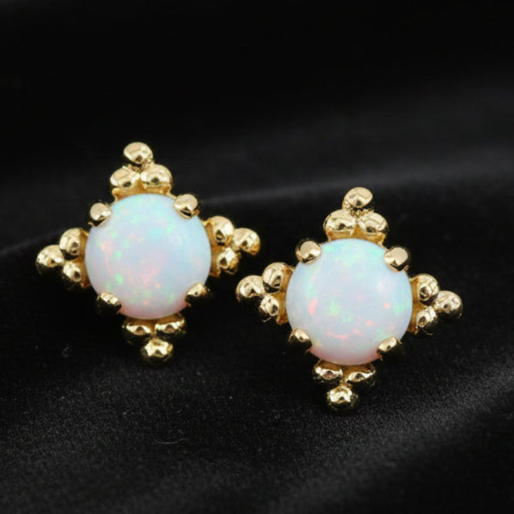 Pair of gold earrings with opal stones on a white background