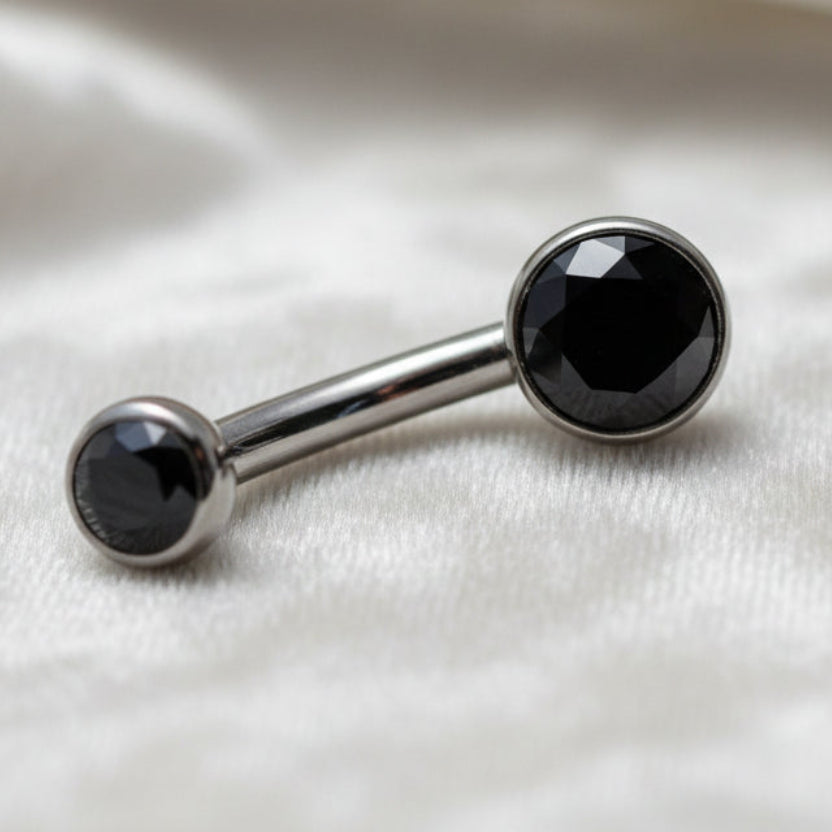 Belly button ring with black gemstones on a white background