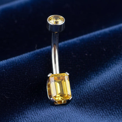 Belly button ring with a yellow gemstone on a white background
