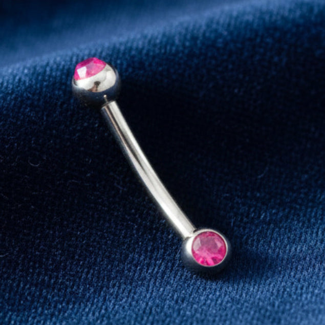 Belly button ring with pink gemstones on a white background