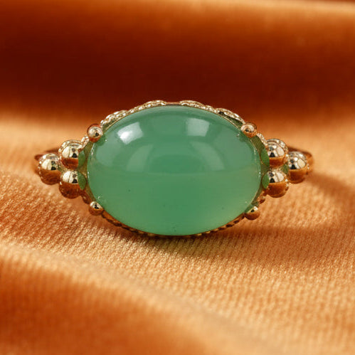 Green gemstone ring with gold setting on a white background