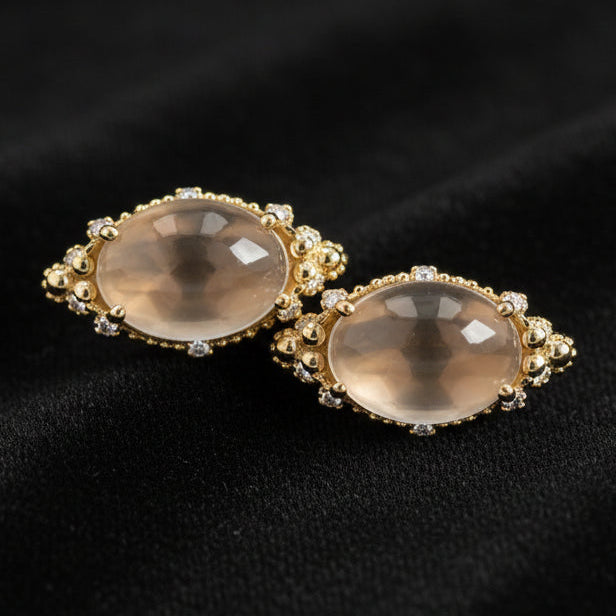 Pair of gold earrings with beige stones on a white background