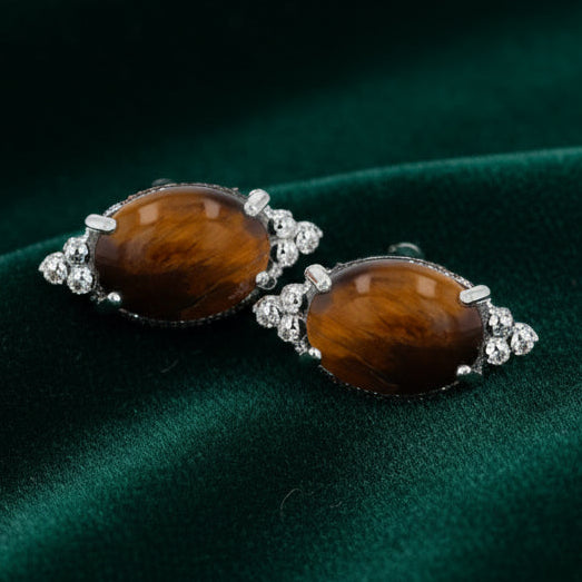 Pair of earrings with brown gemstones and silver accents on a white background