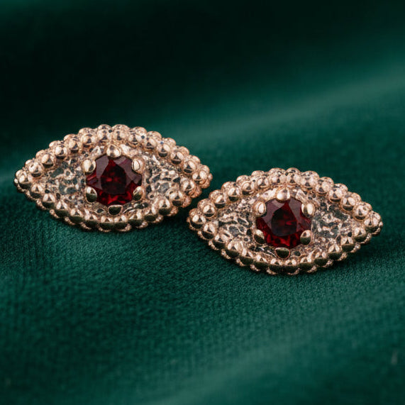 Pair of rose gold earrings with gemstones on a white background