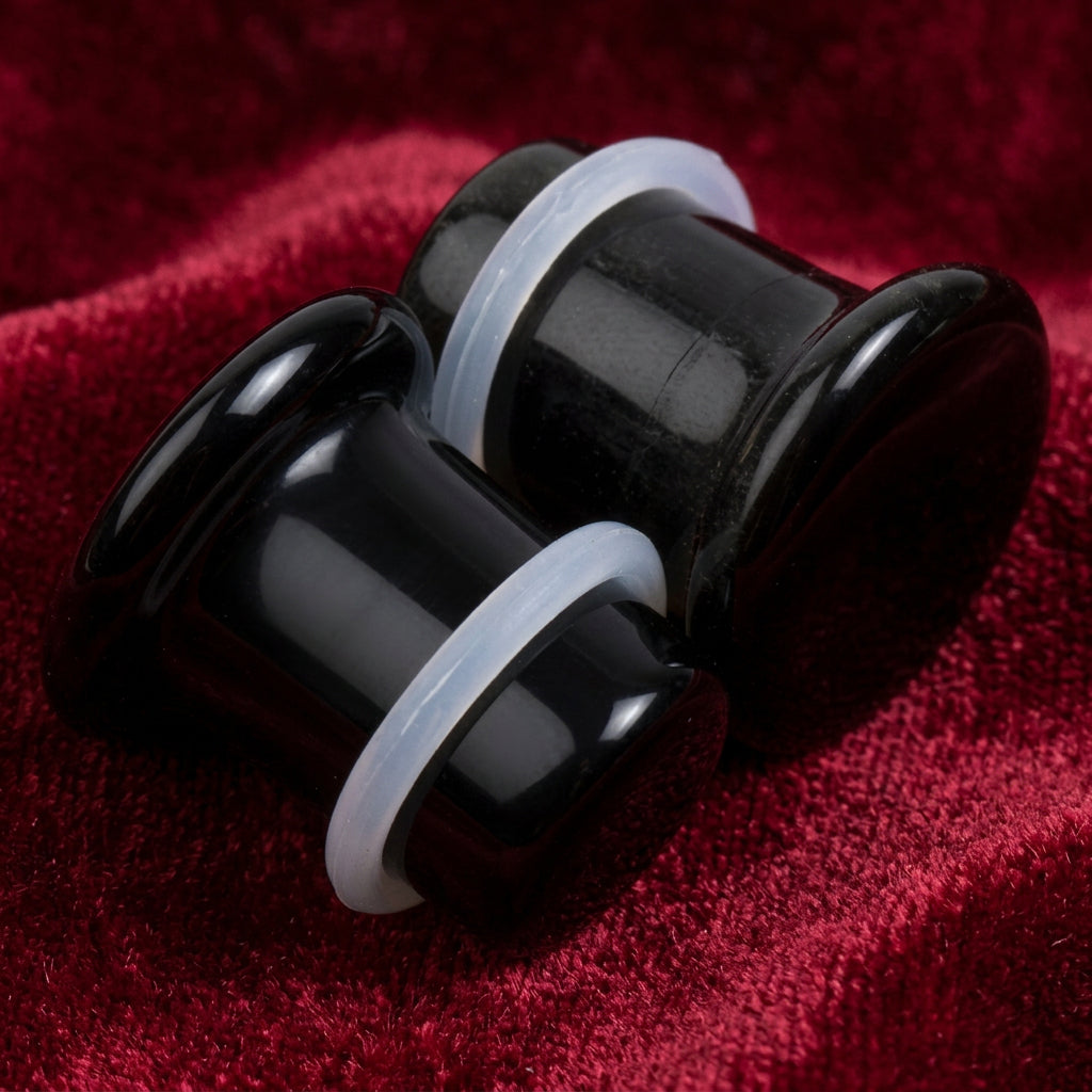 Black glossy labret ear plugs with translucent white silicone rings, shown on a solid white background.