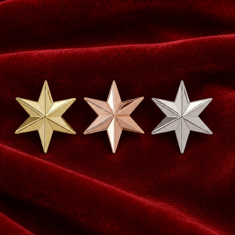 Three metallic star-shaped stud earrings in gold, rose gold, and silver finishes, arranged horizontally on a plain white background.