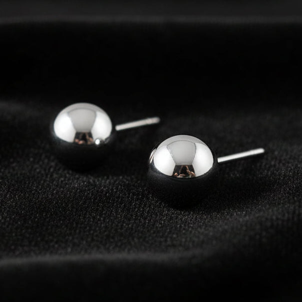 Pair of silver ball earrings on a white background