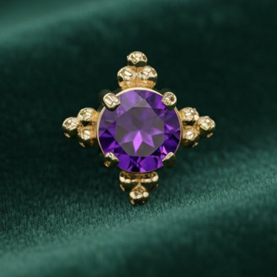 Gold earring with a purple gemstone on a white background