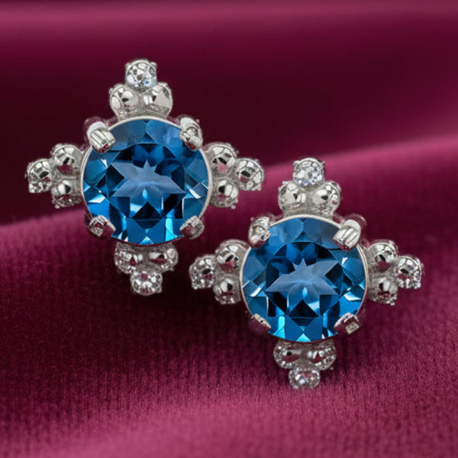 Pair of silver earrings with blue gemstones on a white background