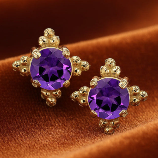 Gold earrings with purple gemstones on a white background