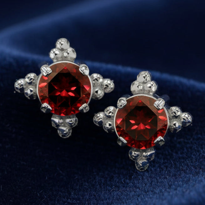 Pair of earrings with red gemstones on a white background